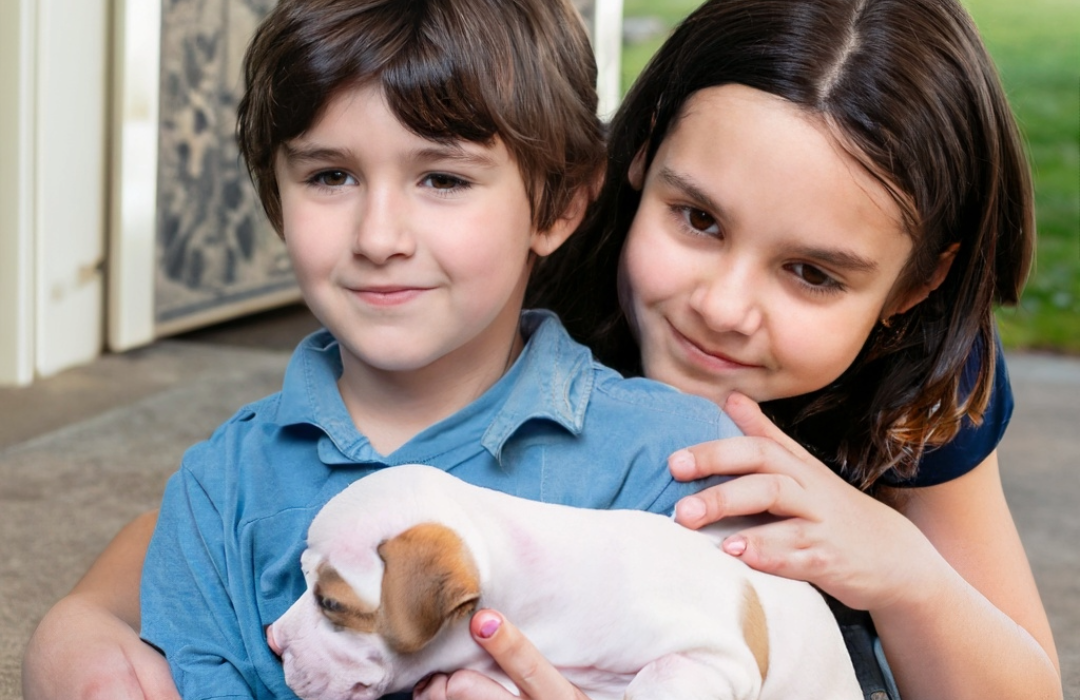 Two children hold their new puppy